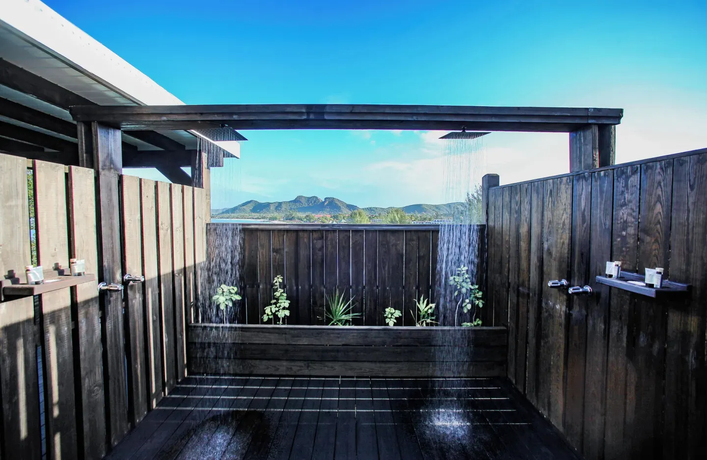 Bay View Pool Cottage outdoor shower with wood walls and hill views at COCOS Hotel.
