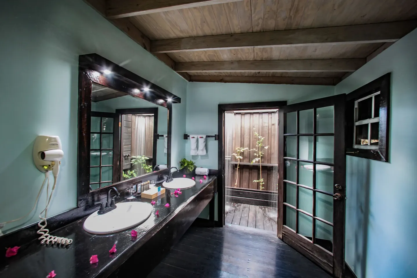 Bathroom vanity and outdoor shower entrance in a Beach Front Pool Cottage at COCOS Hotel.