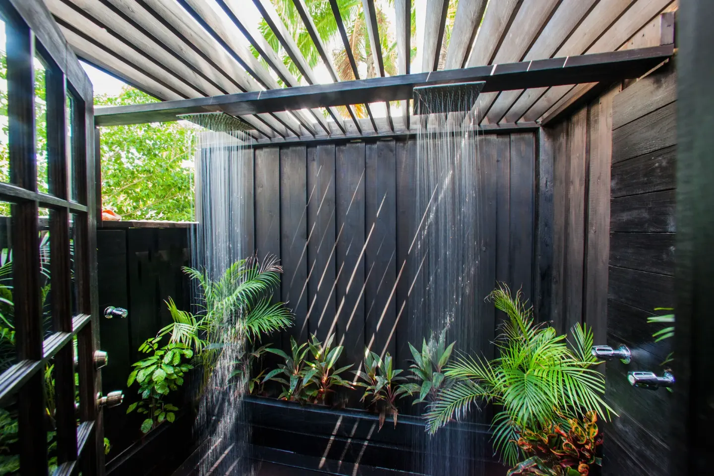 Outdoor shower with tropical plants in a Premium View Cottage at COCOS Hotel.