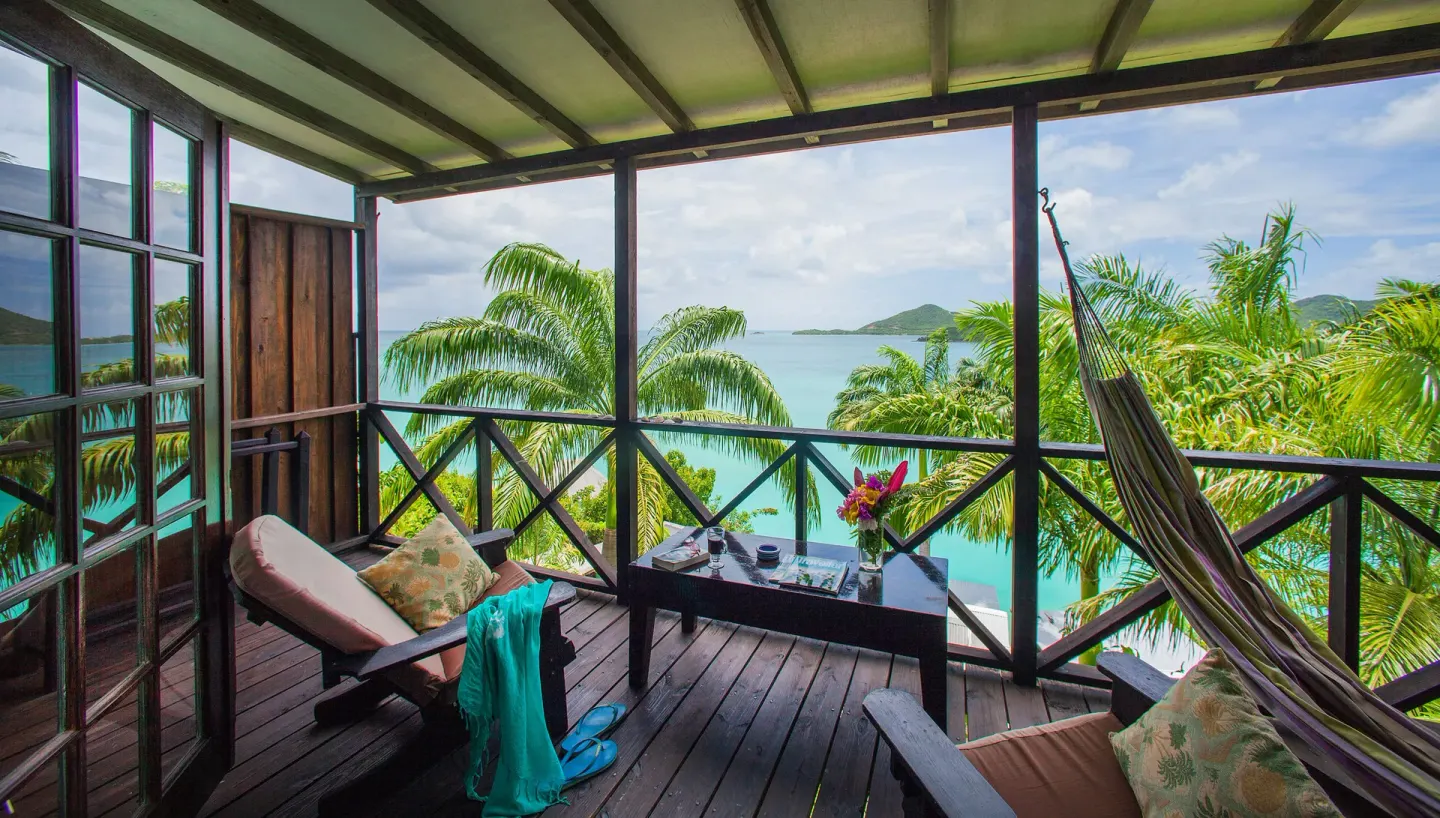 Premium View Cottage veranda seating with hammock and turquoise bay at COCOS Hotel.