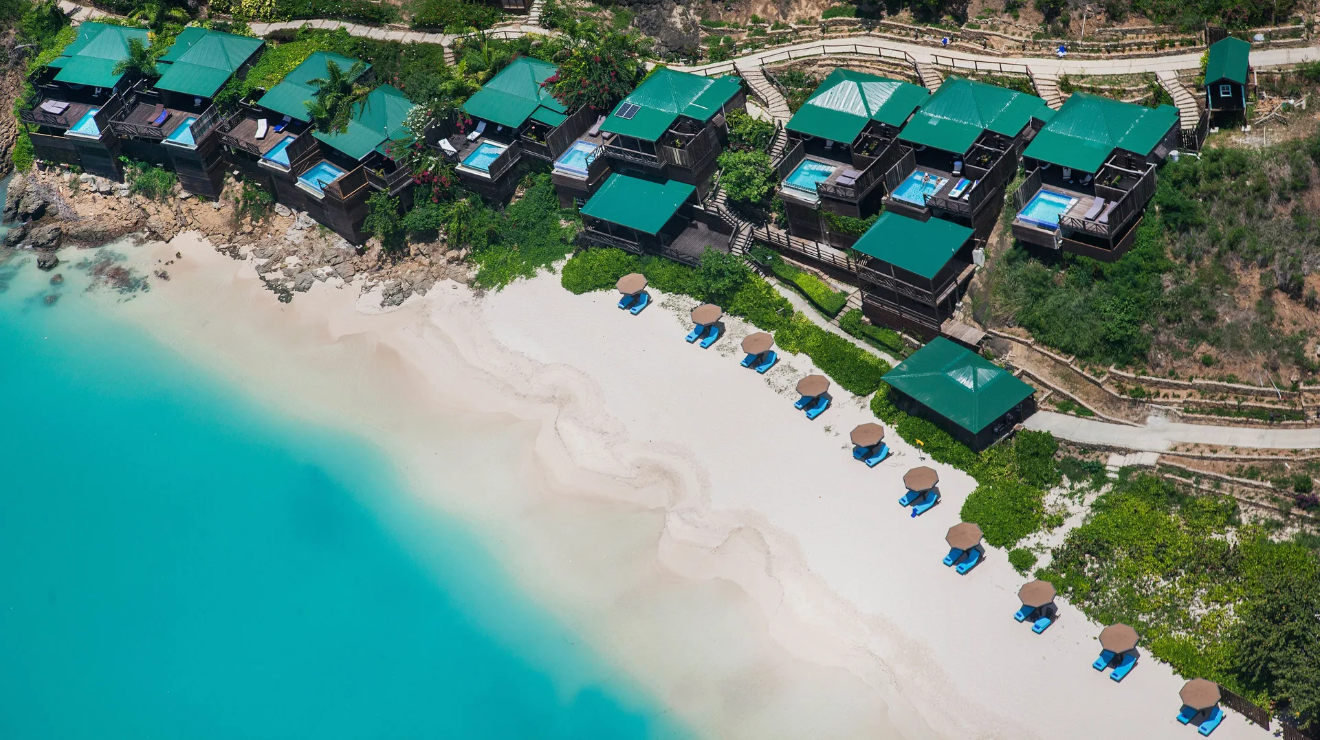 Aerial view of beachfront plunge pool cottages at COCOS Hotel beside turquoise water.