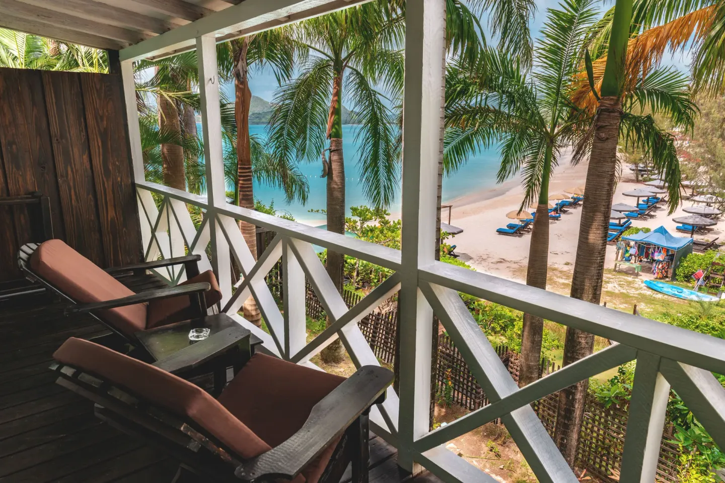 Standard Cottage balcony with lounge chairs overlooking the beach at COCOS Hotel.