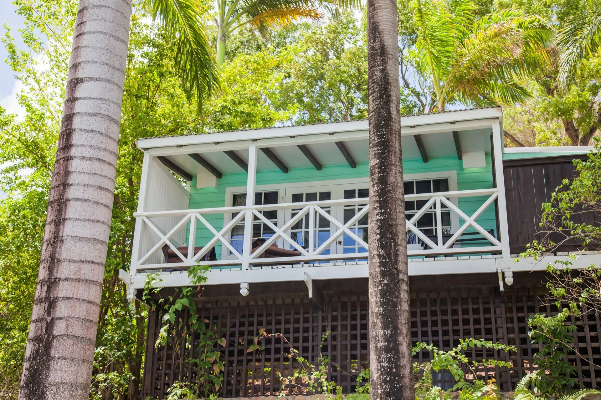 Standard Cottage exterior with white balcony railings and palms at COCOS Hotel.