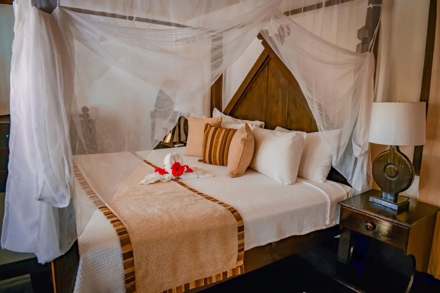 Standard Cottage bed with mosquito net, pillows, and bedside lamp at COCOS Hotel.