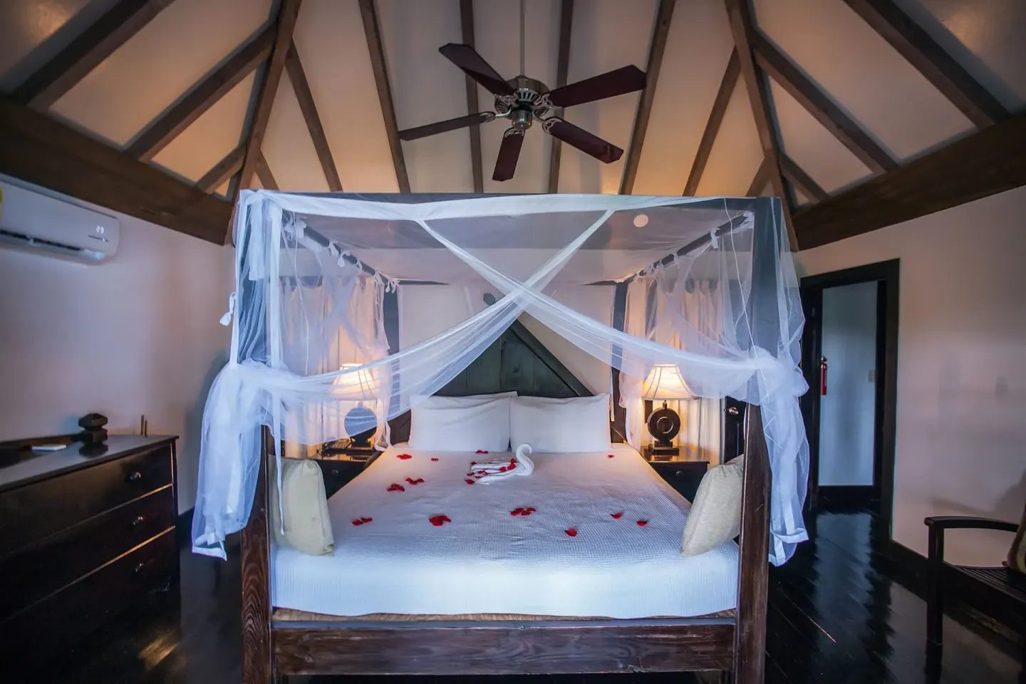 Standard Cottage king bed under a peaked ceiling with netting at COCOS Hotel.