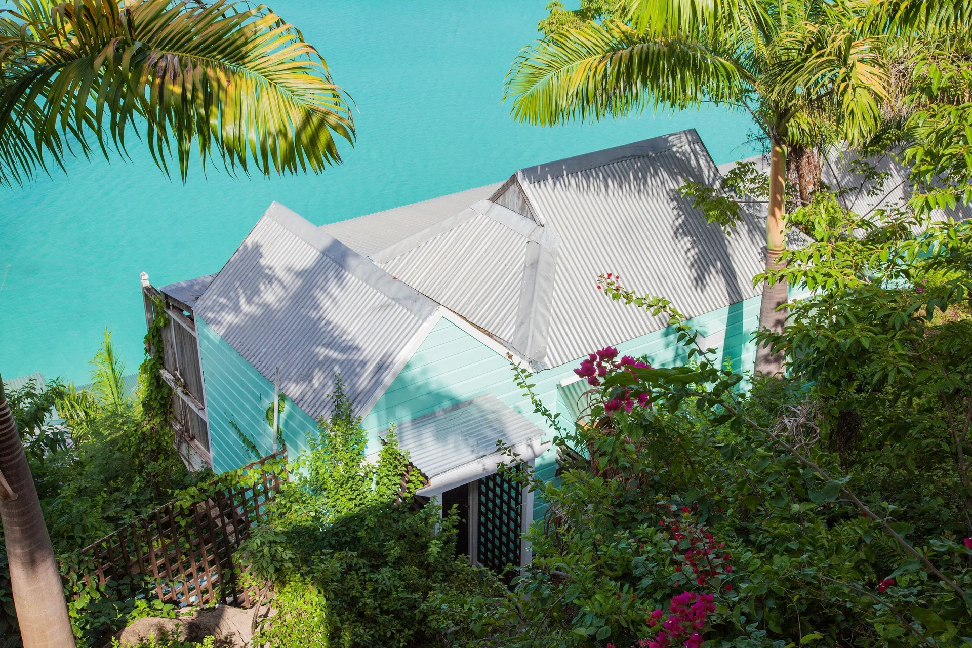 Sunset View Cottage exterior amid palms above turquoise water at COCOS Hotel.