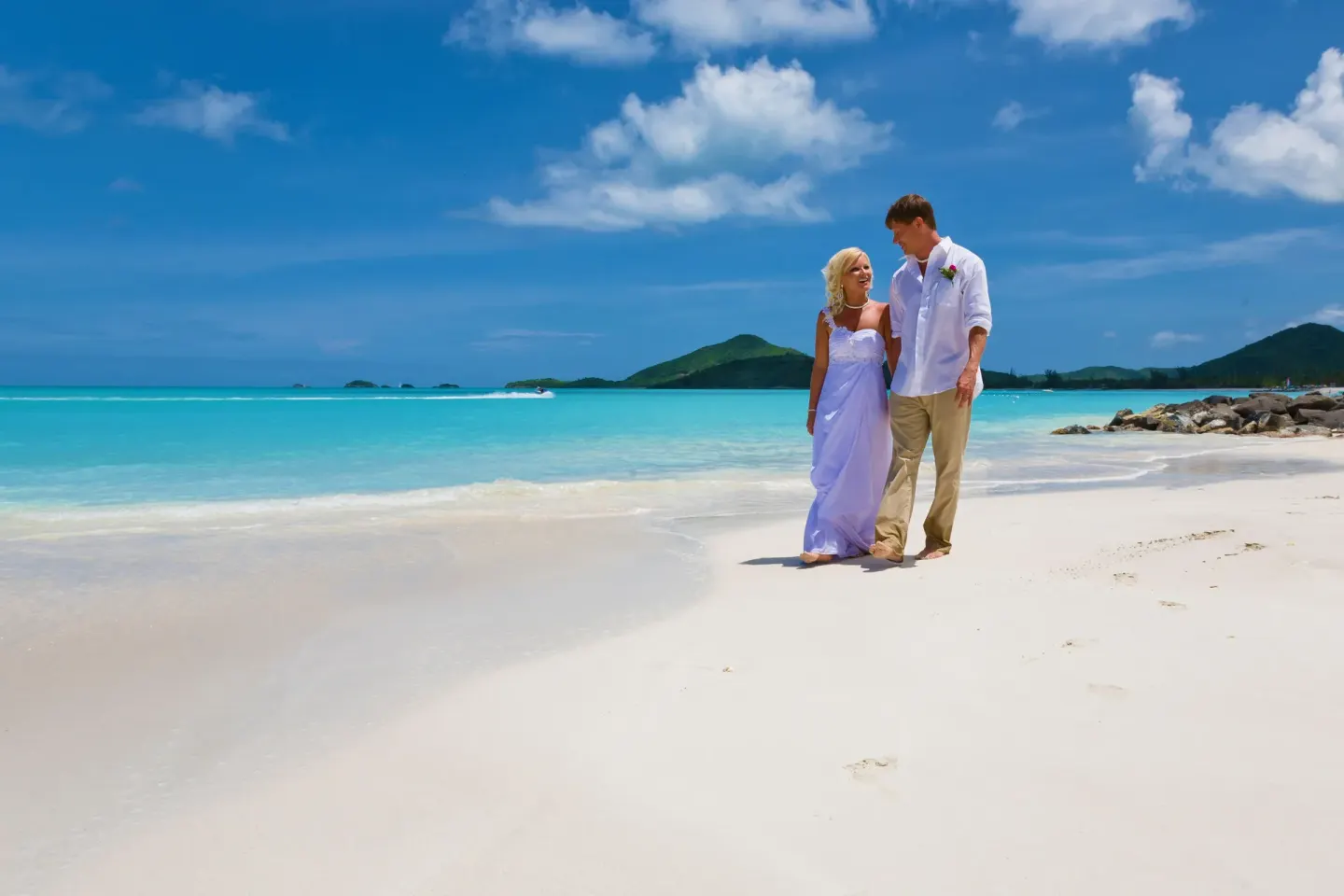 Couple in wedding attire walking on the beach at COCOS Hotel.