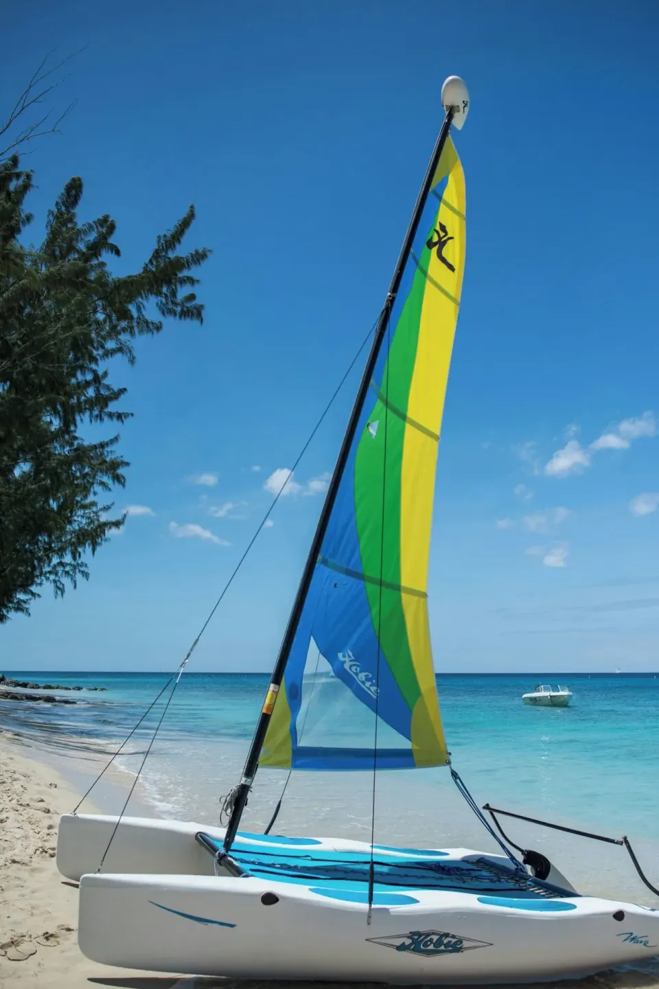 A colorful sailboat rests on the beach beside turquoise water at Colony Club, Barbados.