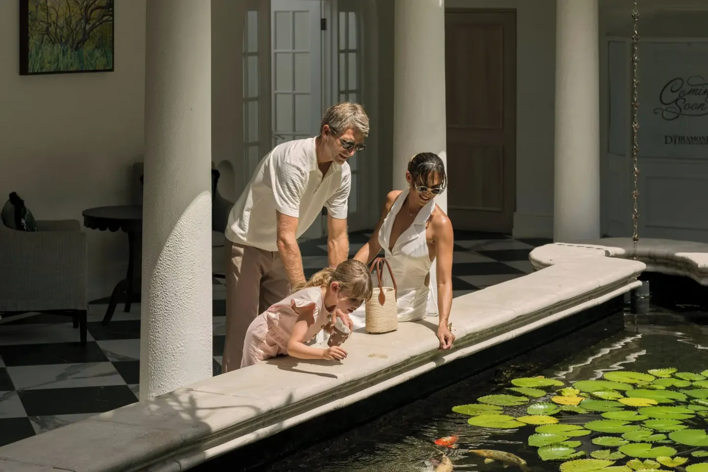 Guests look into a lily pond with fish in a shaded courtyard at Colony Club, Barbados.