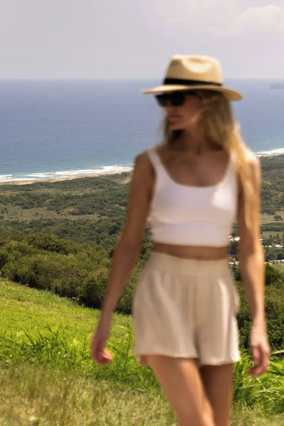 Woman in a sun hat above a green coastline near Colony Club, Barbados.