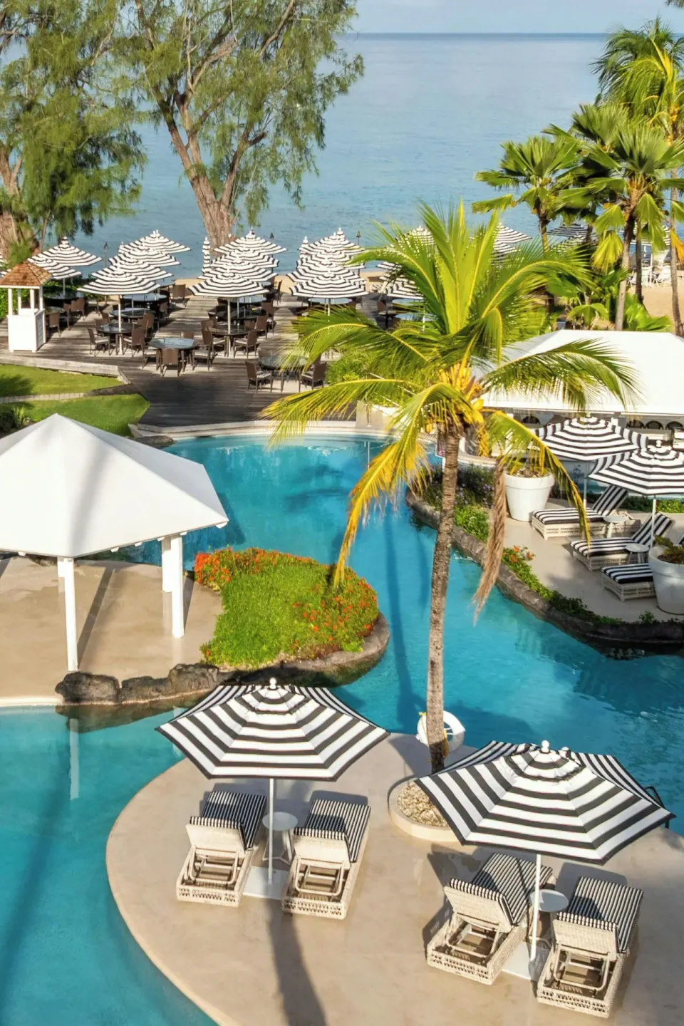 Lagoon pool, striped umbrellas, and sea beyond at Colony Club, Barbados.