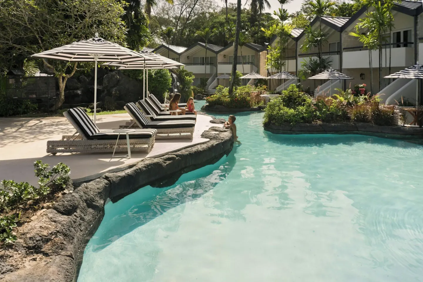 Guests beside a lagoon-style pool and garden rooms at Colony Club, Barbados.