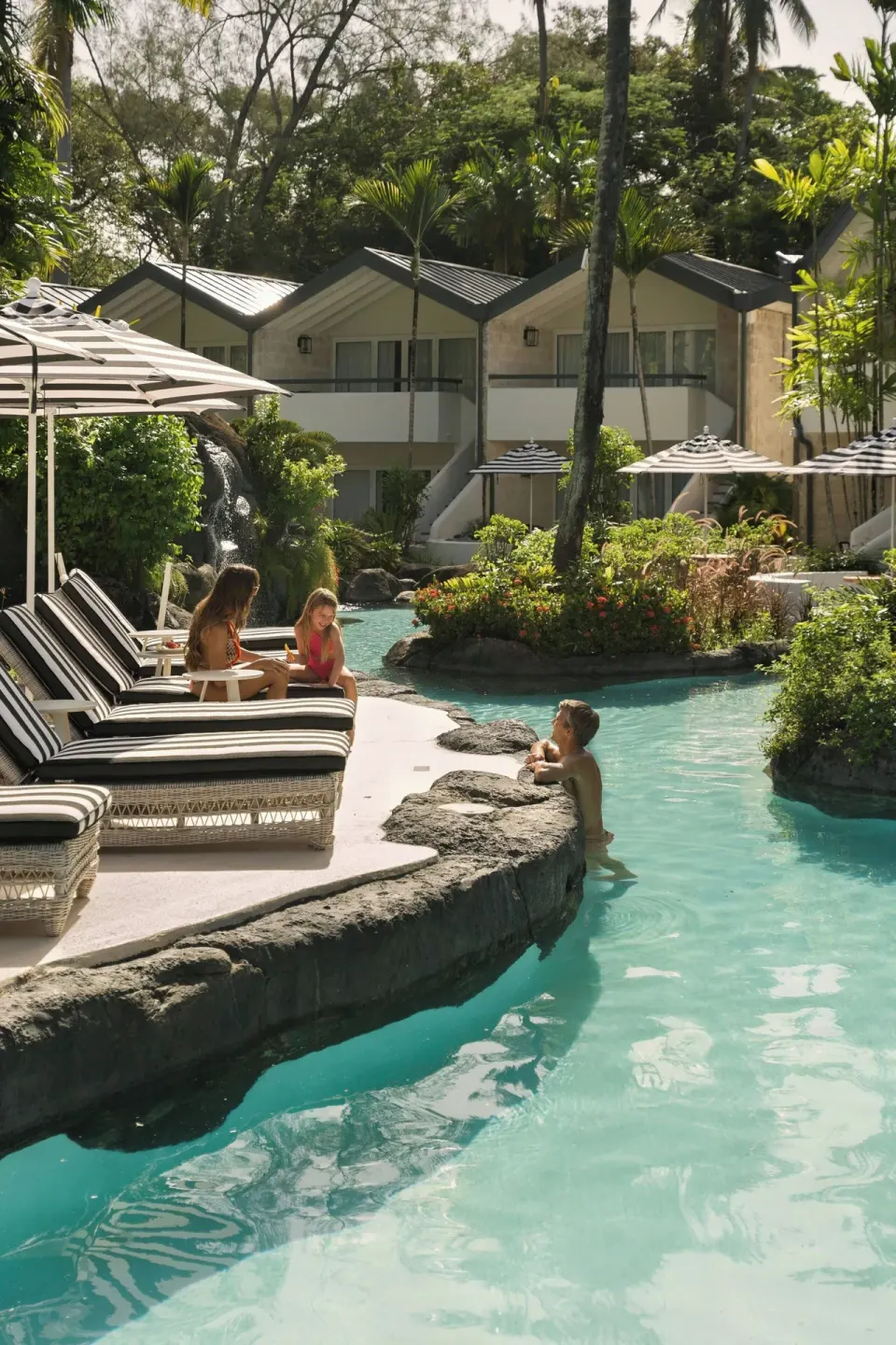 Guests relaxing by the lagoon pool near garden rooms at Colony Club, Barbados.