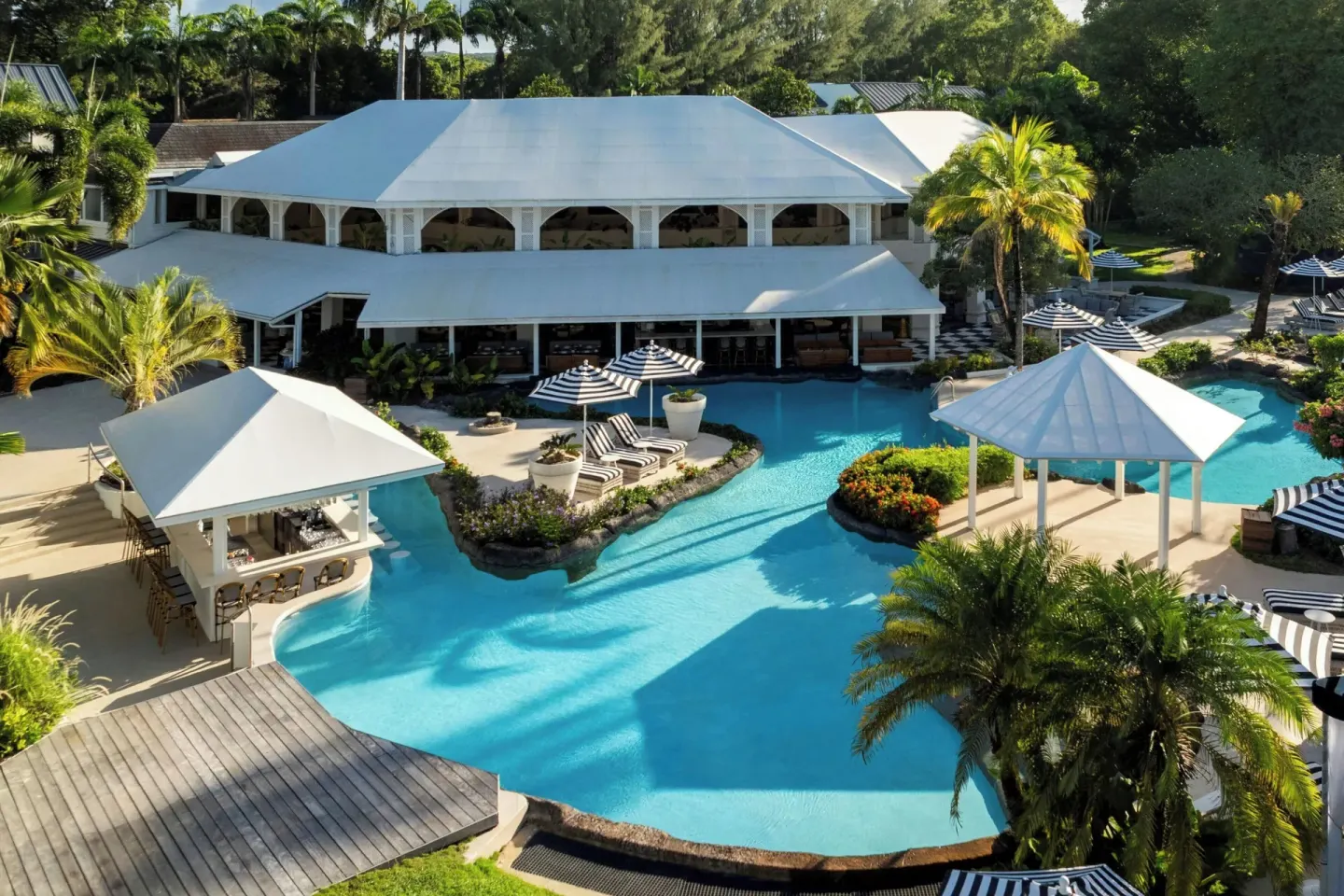 Main pool area with white-roofed pavilions and palm landscaping at Colony Club, Barbados.