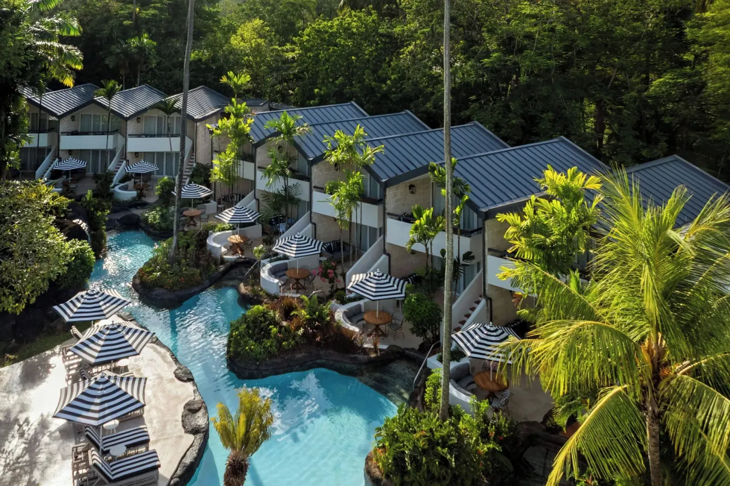 Guest room buildings beside lagoon pools and striped umbrellas at Colony Club, Barbados.