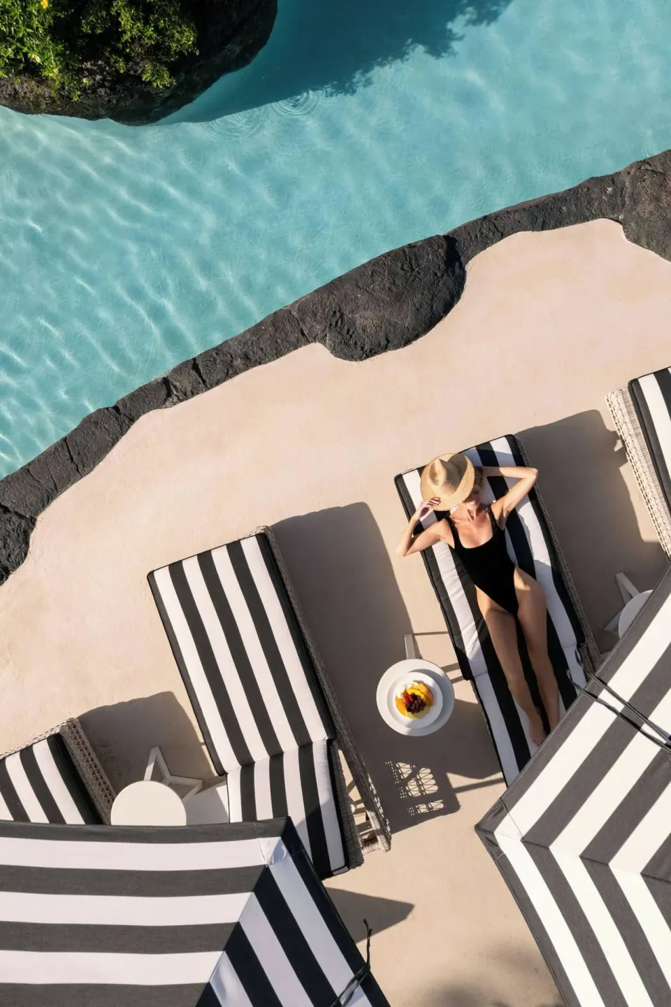 Guest sunbathing on a striped pool lounger at Colony Club, Barbados.
