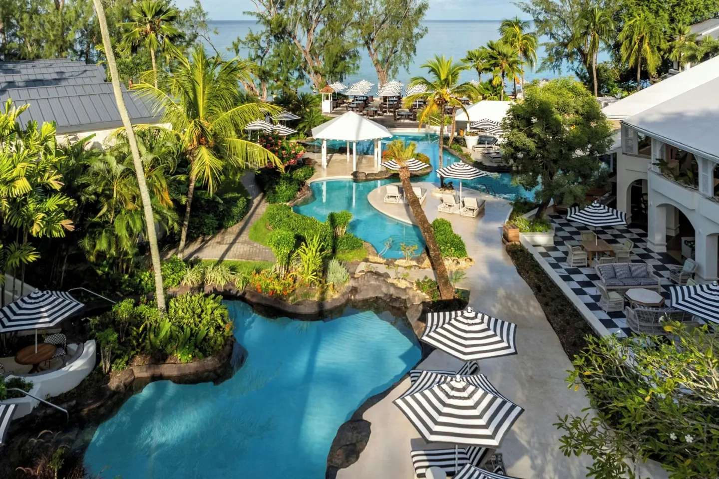 Aerial view of lagoon pools, palms, resort buildings, and sea at Colony Club, Barbados.