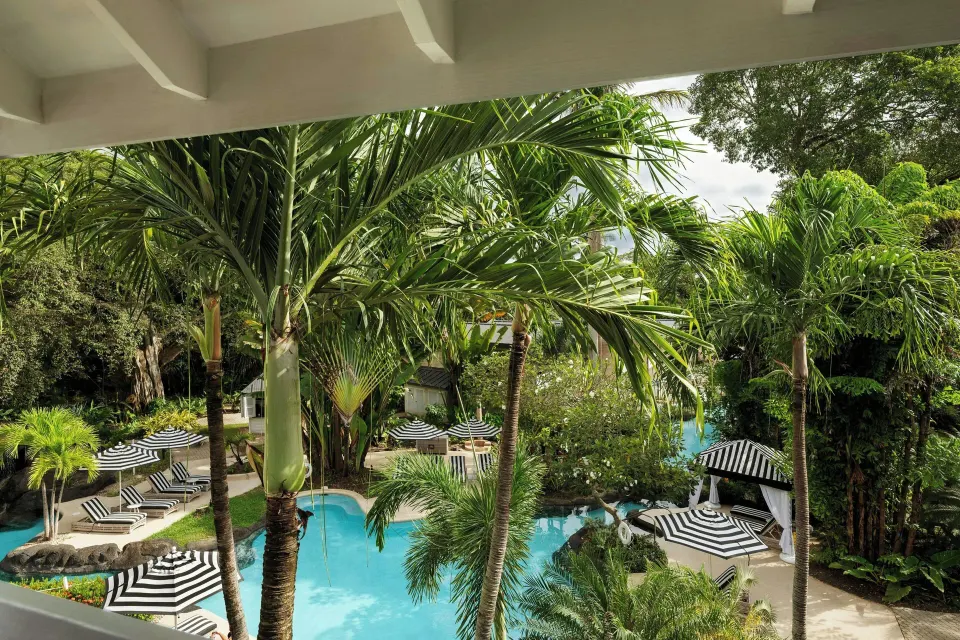 Tropical lagoon pool with striped loungers and palms at Colony Club, Barbados.