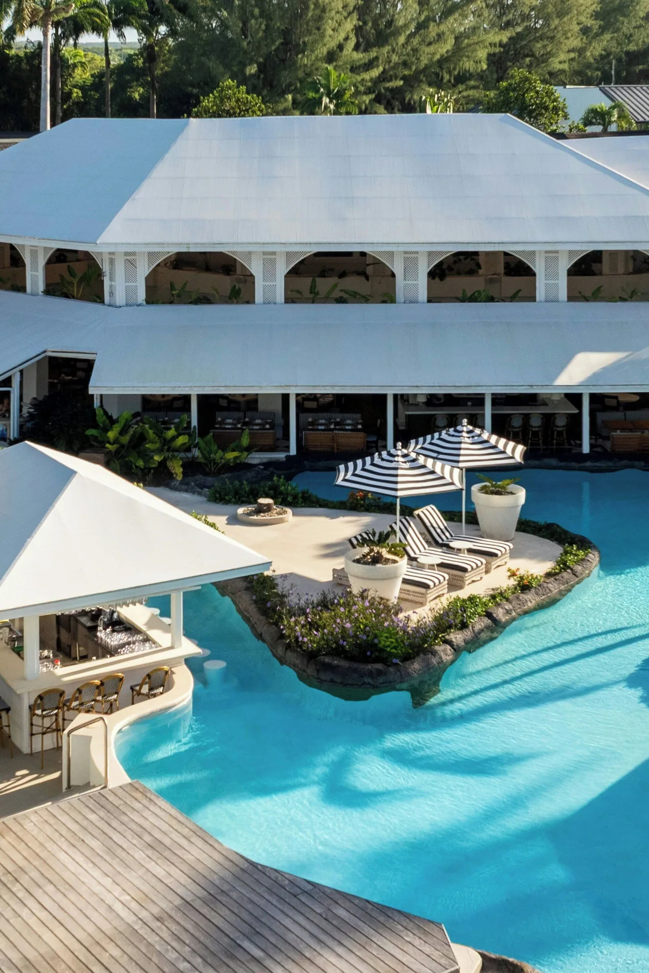 Swim-up pool bar and lagoon pool beside a white resort building at Colony Club, Barbados.