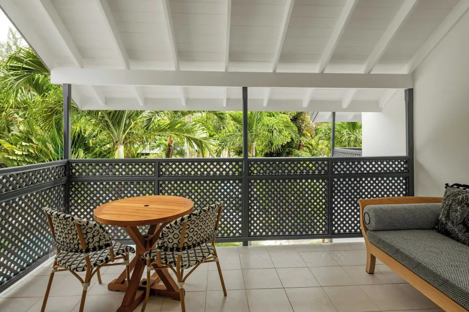 Junior Suite balcony with table, chairs and garden greenery at Colony Club, Barbados.