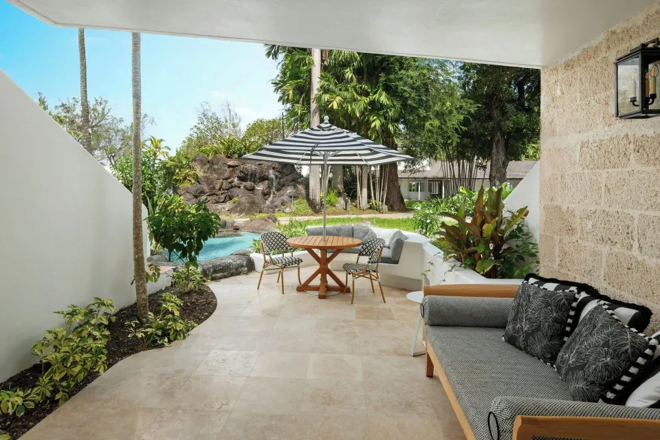 Poolside Luxury Room terrace with sofa and umbrella table at Colony Club, Barbados.