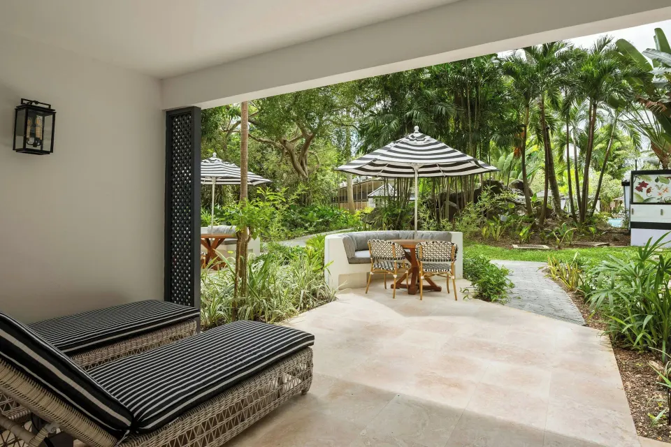 Covered garden patio with loungers and outdoor seating at Colony Club, Barbados.