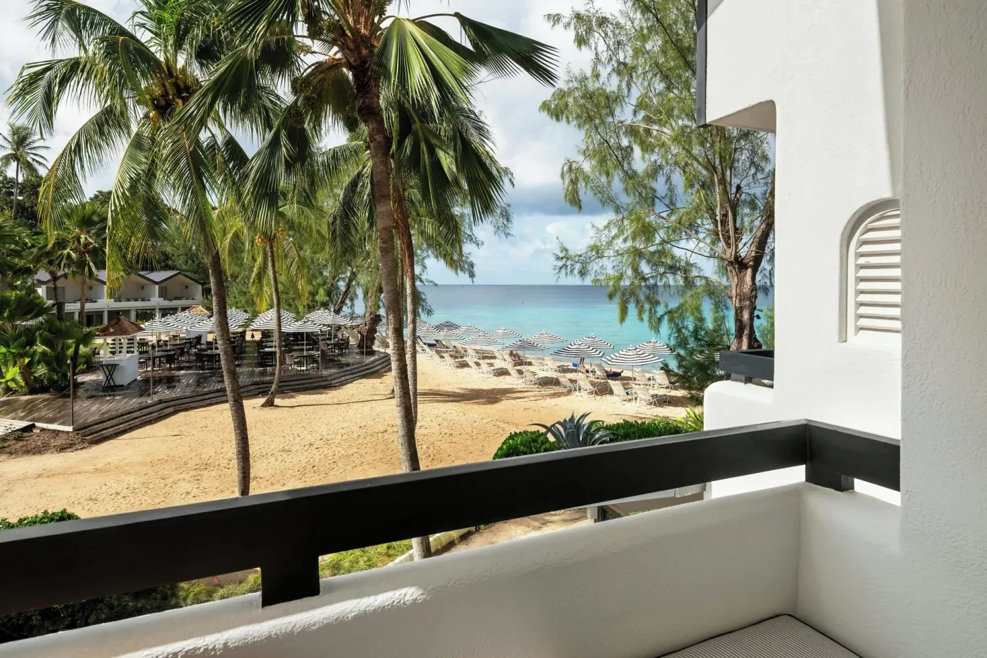 Balcony view of palms, beach umbrellas and ocean at Colony Club, Barbados.