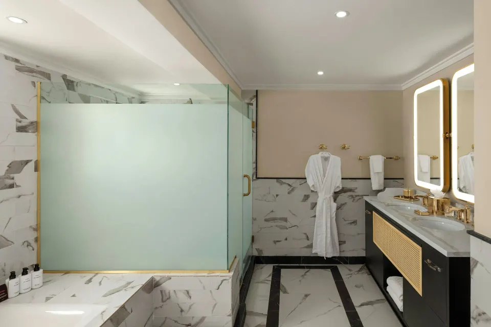 Suite bathroom with tub, frosted glass shower, and double vanity at Colony Club, Barbados.