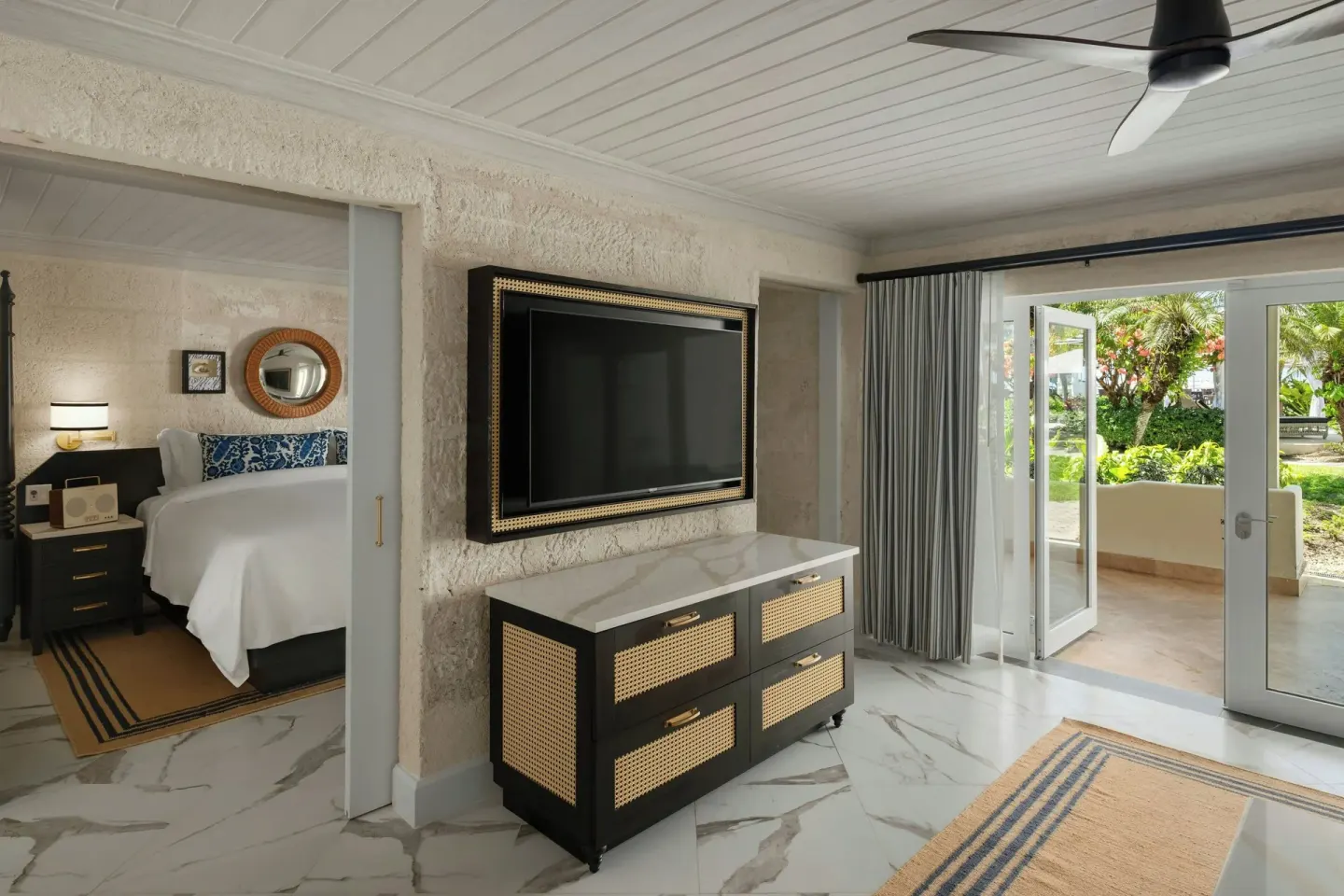 Suite sitting area with TV, open terrace doors, and bedroom beyond at Colony Club, Barbados.