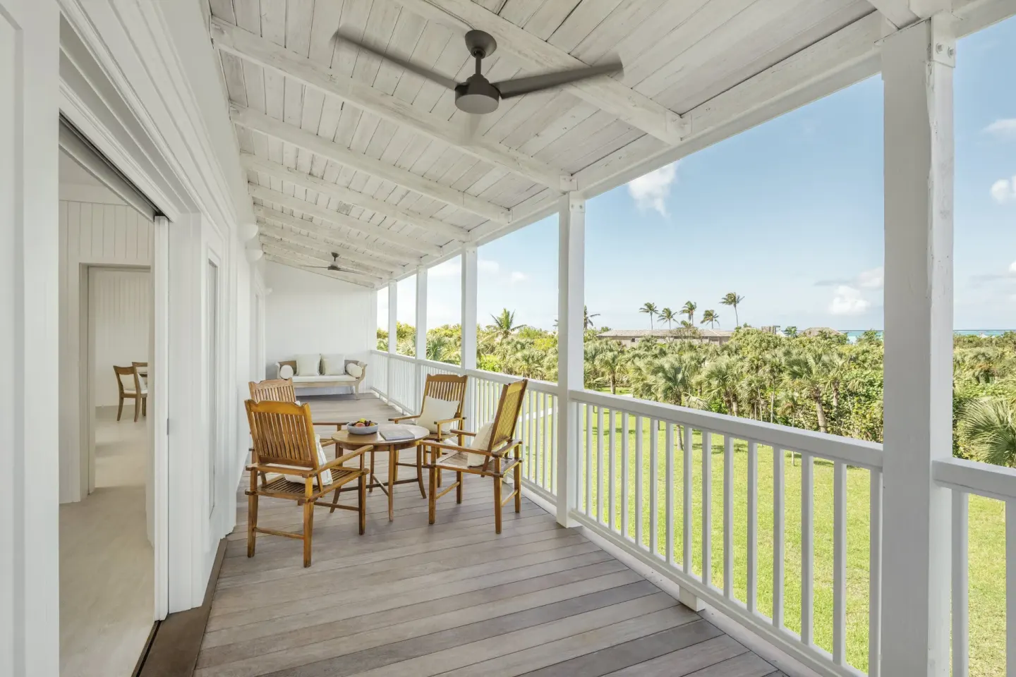 Covered guest room balcony with chairs and palm views at COMO Parrot Cay.