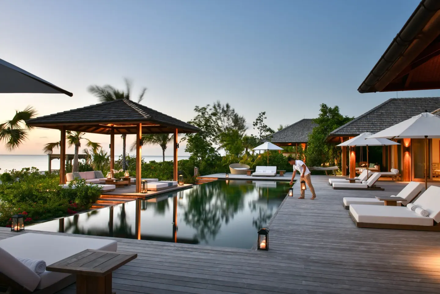 Evening pool deck with cabana, loungers and lanterns at COMO Parrot Cay.