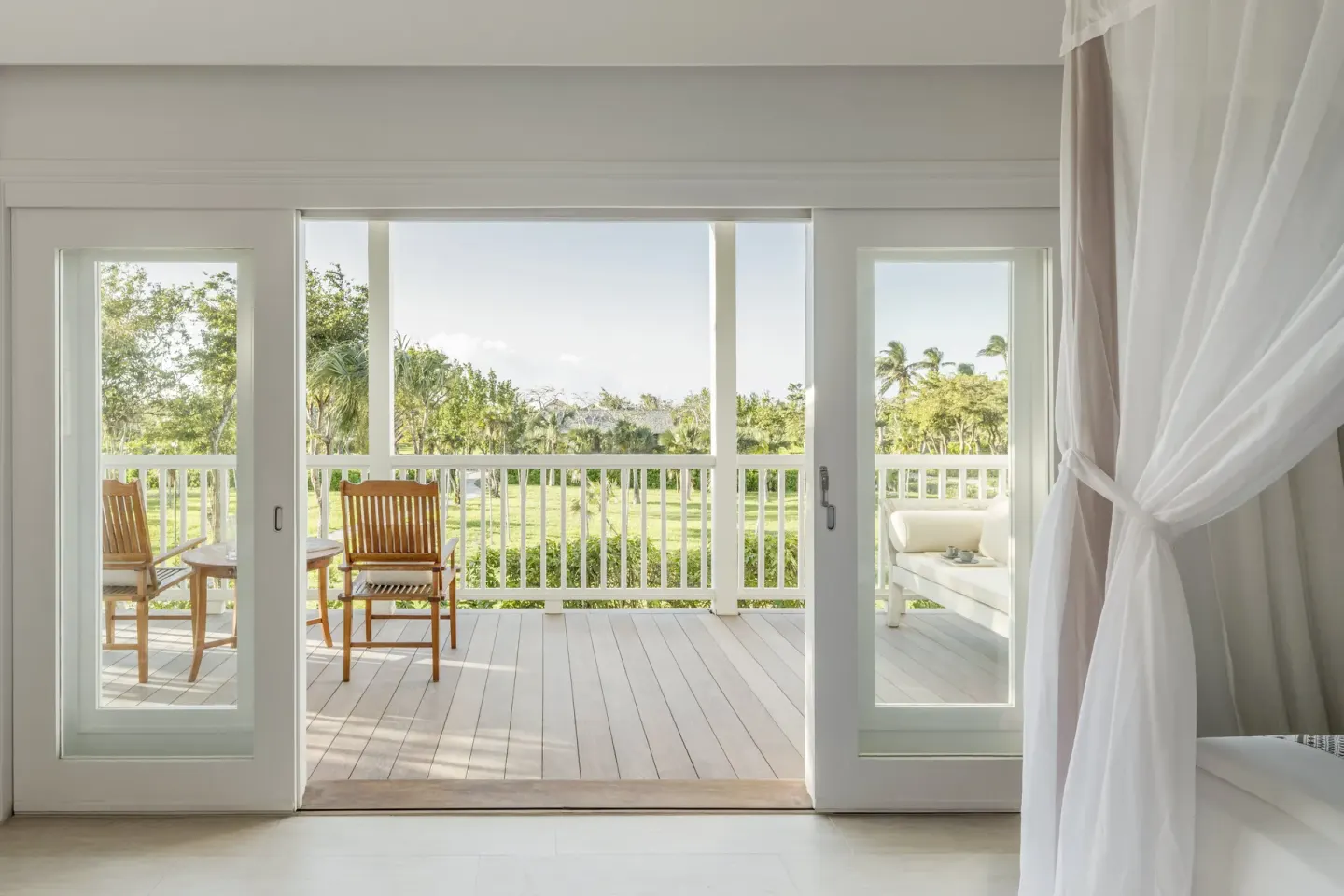 Bedroom doorway opening to a furnished balcony and gardens at COMO Parrot Cay.