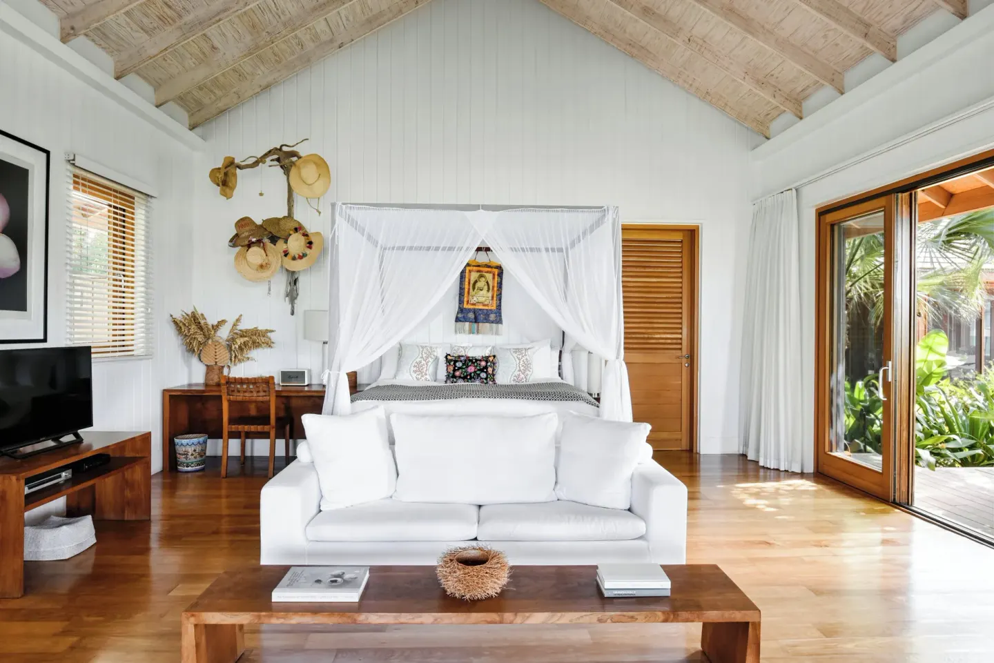 White guest room with four-poster bed and sitting area at COMO Parrot Cay.