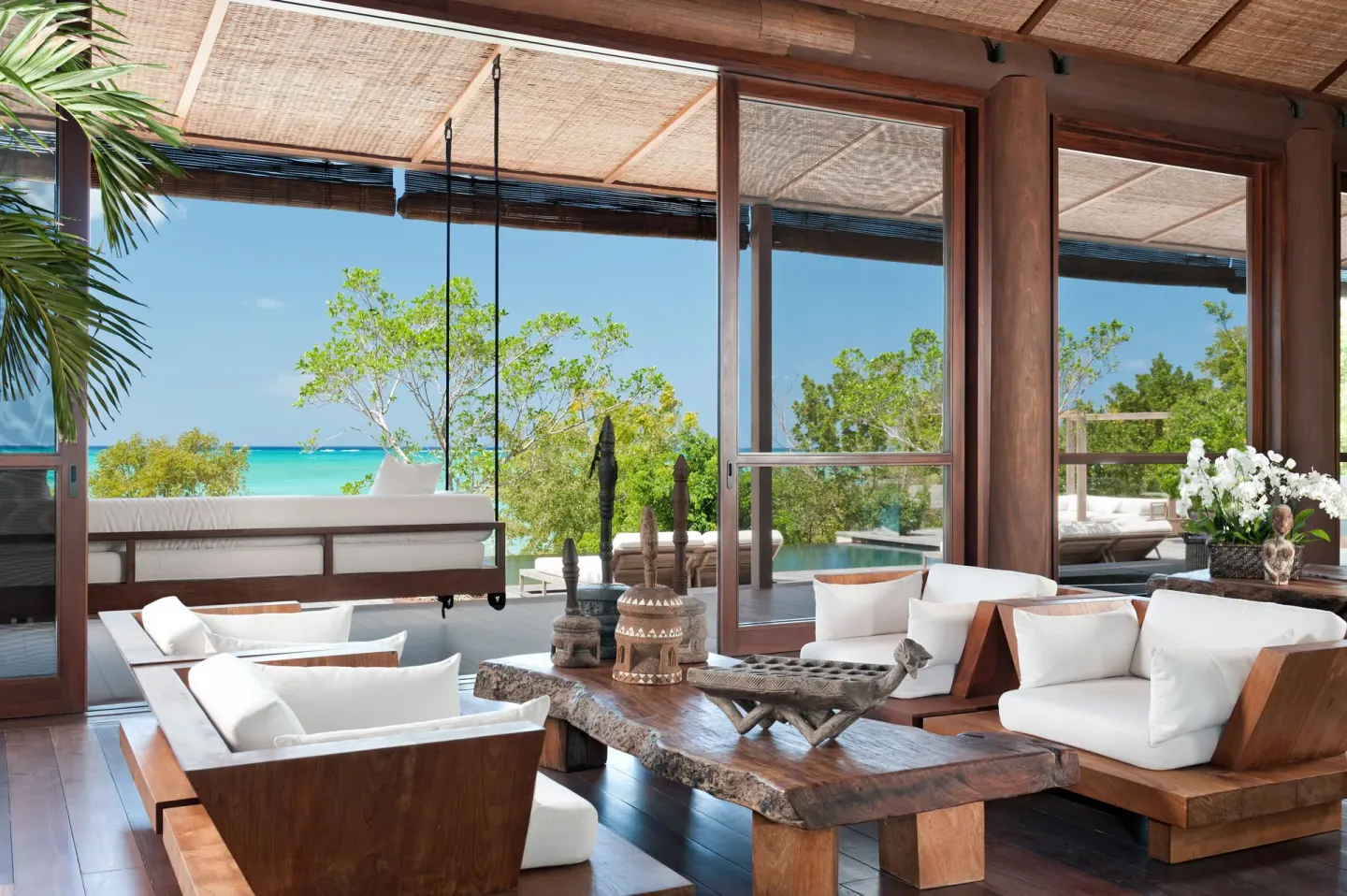 Wooden living room with ocean-facing glass doors at COMO Parrot Cay.