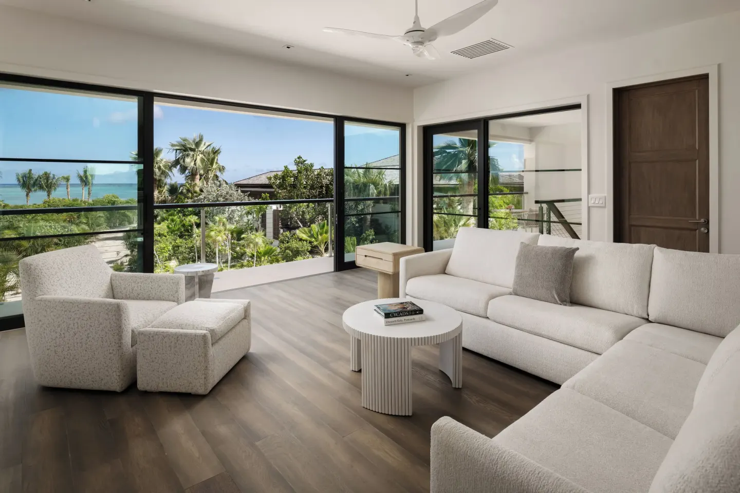 Ocean-view living room at COMO Parrot Cay with cream seating and large glass doors.