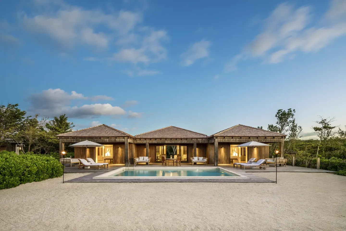 A private villa with a lit pool and loungers at COMO Parrot Cay.
