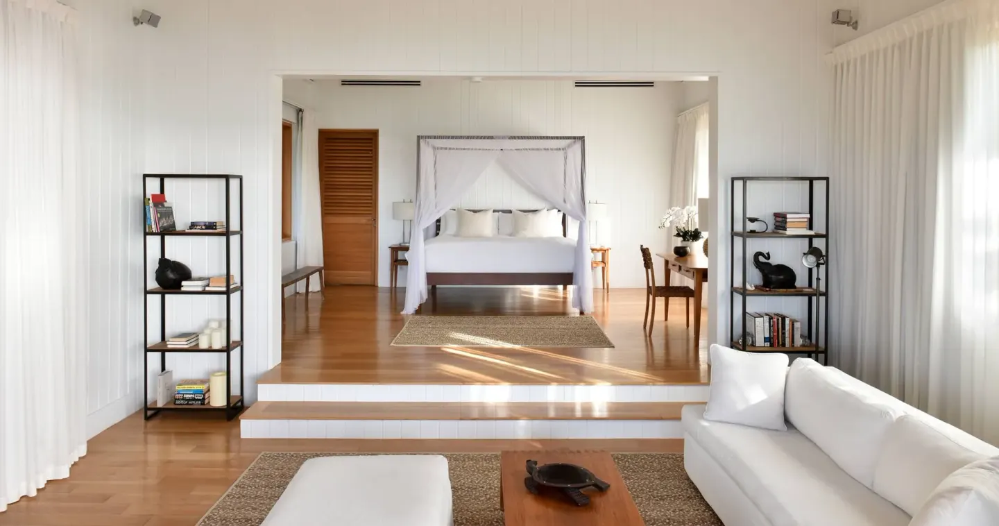 A white bedroom and lounge with a canopy bed at COMO Parrot Cay.