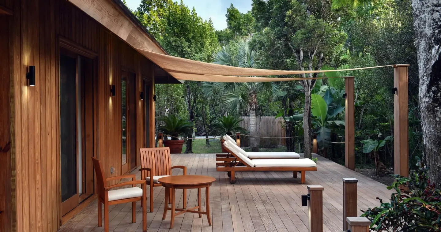 A shaded wooden deck with loungers beside a villa at COMO Parrot Cay.