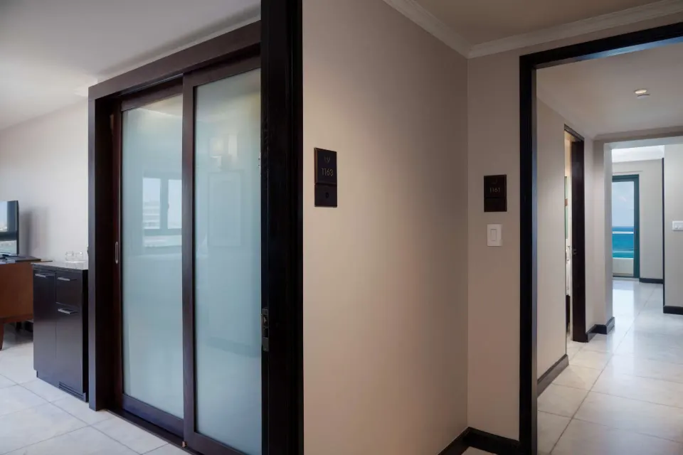 Guest room entry hall at Condado Vanderbilt Hotel with sliding frosted doors and ocean glimpses beyond.