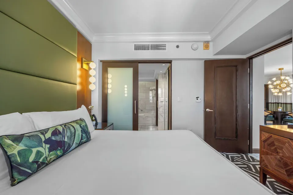 King bed and bathroom doorway in a guest room at Condado Vanderbilt Hotel.