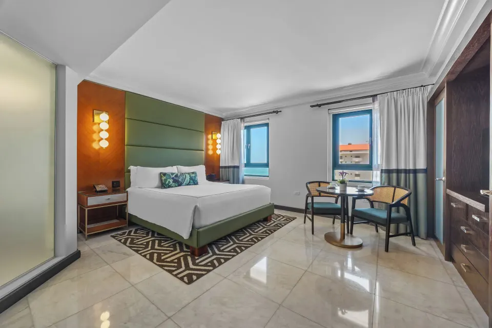 King bed and corner sitting area with ocean glimpses at Condado Vanderbilt Hotel.