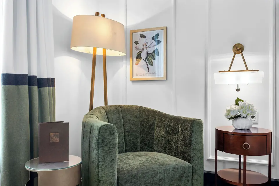 Guest room reading corner with green armchair, floor lamp and side table at Condado Vanderbilt Hotel.