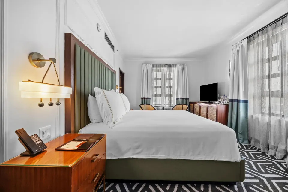 King guest room at Condado Vanderbilt Hotel with bedside desk phone, window seating, and TV console.
