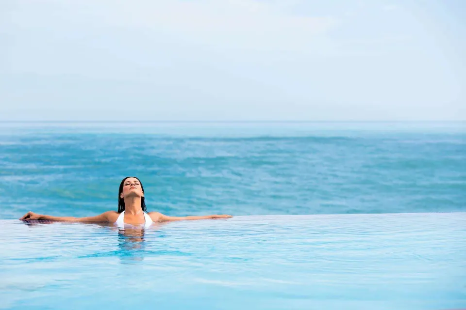 Guest floats in an infinity pool overlooking the ocean at Condado Vanderbilt Hotel.