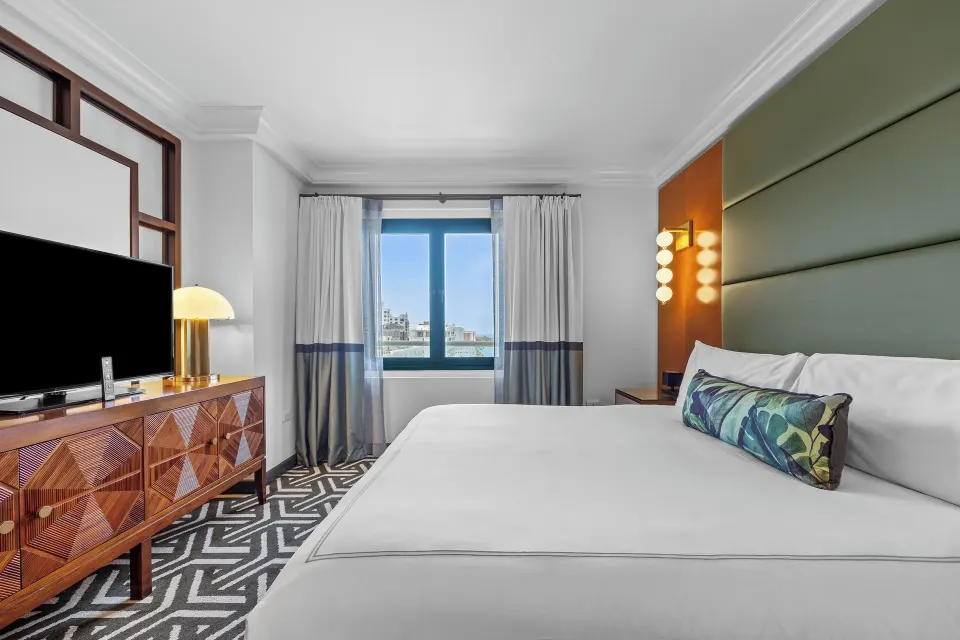 King guest room with green paneled wall and window view at Condado Vanderbilt Hotel.