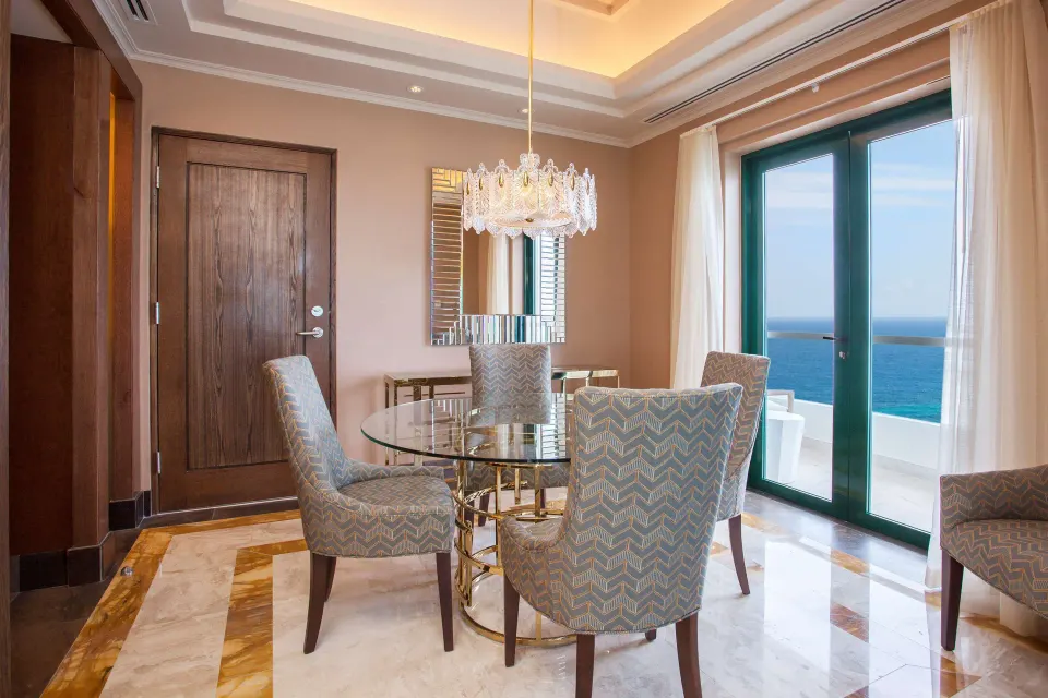 Ocean-view dining table with chandelier inside a suite at Condado Vanderbilt Hotel.