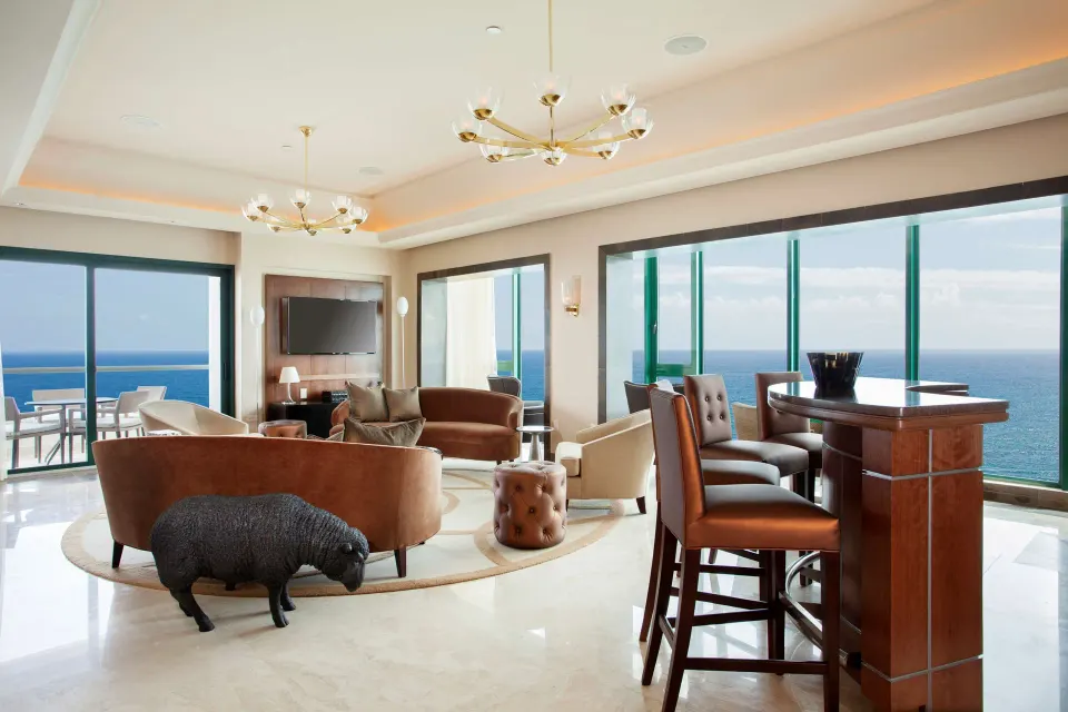 Oceanfront suite living room with seating and wet bar at Condado Vanderbilt Hotel.