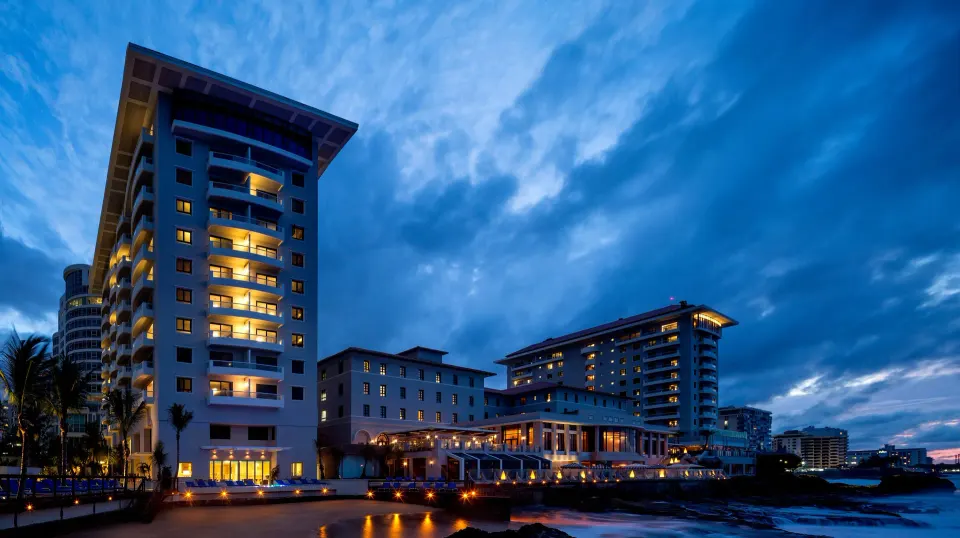 Illuminated oceanfront towers of Condado Vanderbilt Hotel at dusk.