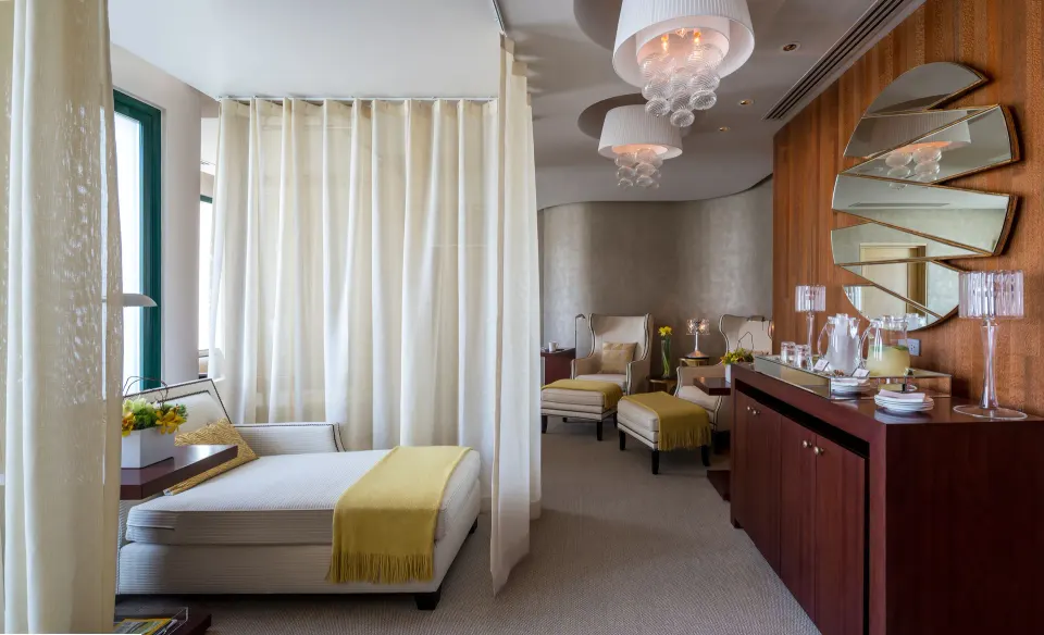 Spa relaxation room with loungers, curtains, and vanity at Condado Vanderbilt Hotel.