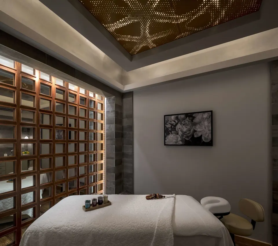 Spa treatment room with massage table and warm ceiling detail at Condado Vanderbilt Hotel.
